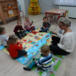 nauczyciel i dzieci bawią się na dywanie