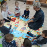nauczyciel i dzieci bawią się na dywanie