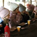 Dzieci jedzą kiełbaskę z rożna