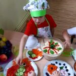 Dzieci układają sowę i rybkę z warzyw i owoców