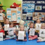 Dzieci prezentują ilustracje zwierząt zamieszkujących Arktykę i Antarktydę