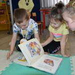 Dzieci z zaciekawieniem oglądaja książkę o przygodach Kubusia Puchatka