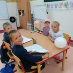 Dzieci siedzą przy stoliku z uczniami