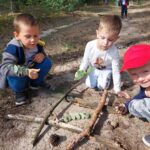 Chłopcy grają w kółko i krzyżyk darami lasu