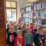 Dzieci stoją pomiędzy regałami z książkami