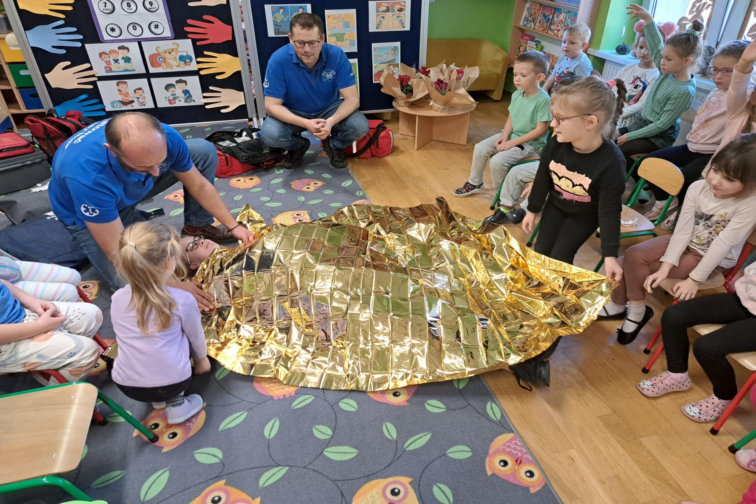 Dzieci okrywają poszkodowanego kocem termicznym