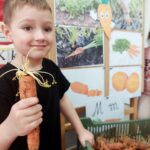 12. Chłopiec pozuje z marchewką z eko uprawy