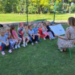 Nauczycielka czyta dzieciom bajkę na podwórku