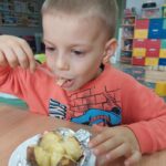 Chłopiec je z apetytrm ziemniaka w mundurku