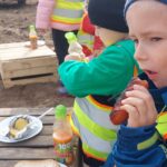 Dzieci jedzą smaczną kiełbasę prosto z ogniska