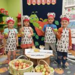 Dzieci w fartuszkach prezentują co można zrobić z jabłek