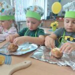 Dzieci wsadzają do ziemniaczków żółty ser