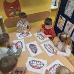 Dzieci na ilustracji myją szczoteczkami zęby