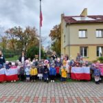 Dzieci śpiewają hymn Polski pod wciągniętą flagą na maszt