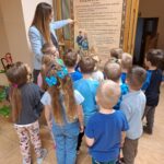 Dzieci z nauczycielką przy kodeksie praw dziecka wywieszonym na drzwiach przedszkola