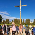 Pani katechetka opowiada dzieciom na cmentarzu o Święcie Zmarłych