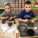 Dzieci uzupełniają domki z gliny