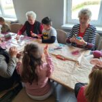 dzieci z seniorami ozdabiają pisanki