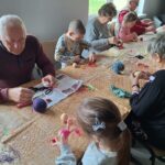 dzieci z seniorami ozdabiają pisanki