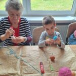 dzieci z seniorami ozdabiają pisanki