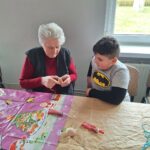 dzieci z seniorami ozdabiają pisanki