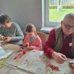 dzieci z seniorami ozdabiają pisanki