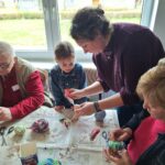 dzieci z seniorami ozdabiają pisanki