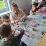 dzieci z seniorami ozdabiają pisanki