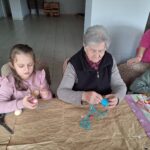 dzieci z seniorami ozdabiają pisanki