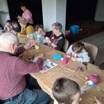 dzieci z seniorami ozdabiają pisanki