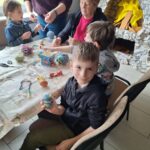 dzieci z seniorami ozdabiają pisanki