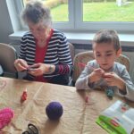 dzieci z seniorami ozdabiają pisanki