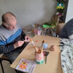 dzieci z seniorami ozdabiają pisanki