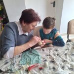 dzieci z seniorami ozdabiają pisanki