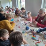 dzieci z seniorami ozdabiają pisanki
