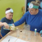 Chłopiec leje olej do szklanki