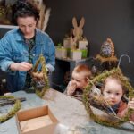 Dzieci pod czujnym okiem florysty ozdabiają wianki