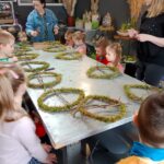 Dzieci przystępują do ozdabiania wianków z mchu