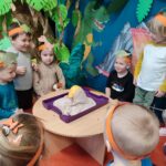 Dzieci wraz z Panią ulepiły wulkan i robią doświadczenie.