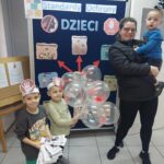 Dzieci z oddziału Krasnoludki wręczają rodzicom broszury informacyjne nt gdzie szukać pomocy oraz balony z odbitą rączką