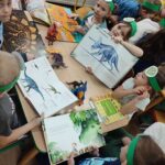 Przedszkolaki oglądają albumy z dinozaurami