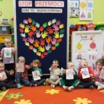 Przedszkolaki z oddziału Żuczki na wspólnym zdjęciu przy tablicy edukacyjnej