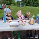 Dzieci siedzą i jedzą kiełbaski