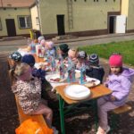 Dzieci siedzą i jedzą kiełbaski