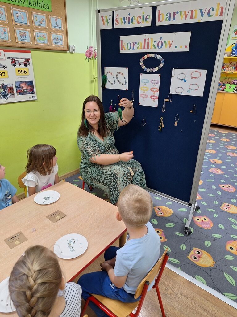 Pani Karolina pokazuje dzieciom koraliki