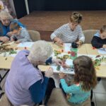 dzieci wraz z seniorami przyklejają liście