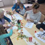 dzieci wraz z seniorami przyklejają liście