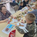 dzieci wraz z seniorami przyklejają liście