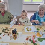dzieci wraz z seniorami przyklejają liście