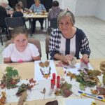 dzieci wraz z seniorami przyklejają liście